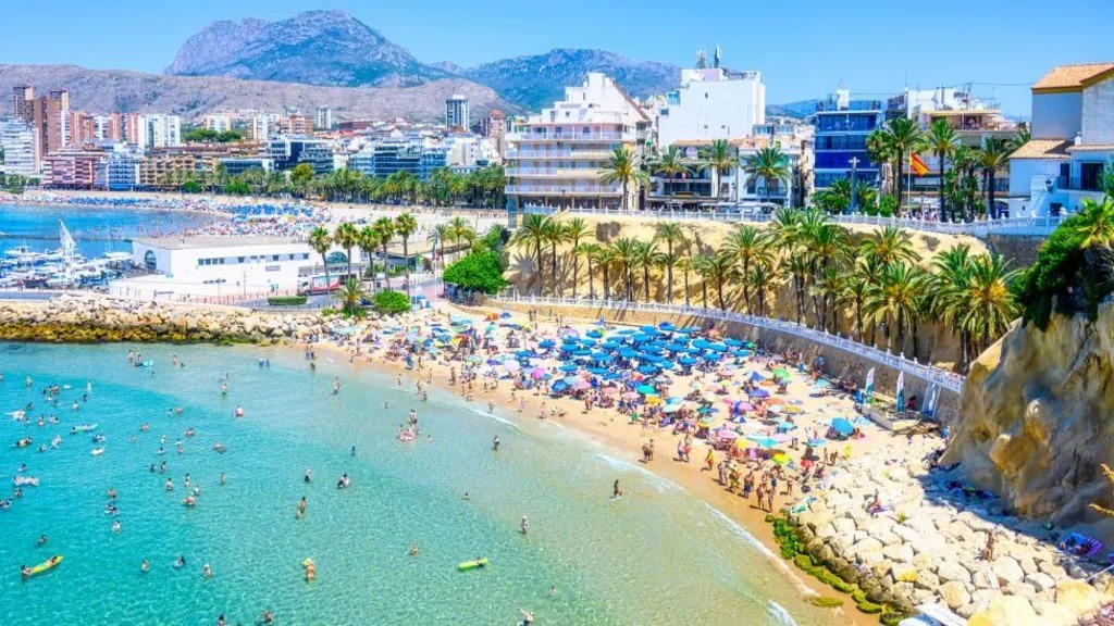 Tourists waiting at a hotel check-in desk in Spain amid new data collection rules.